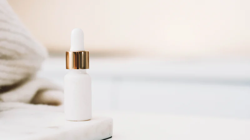 Lọ serum nhỏ giọt màu trắng đặt trên nền sáng