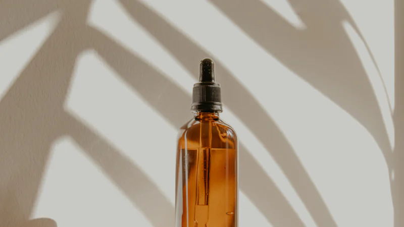 Chai thủy tinh màu hổ phách có ống nhỏ giọt đặt trên bệ gỗ, minh họa cách đóng gói serum vitamin C