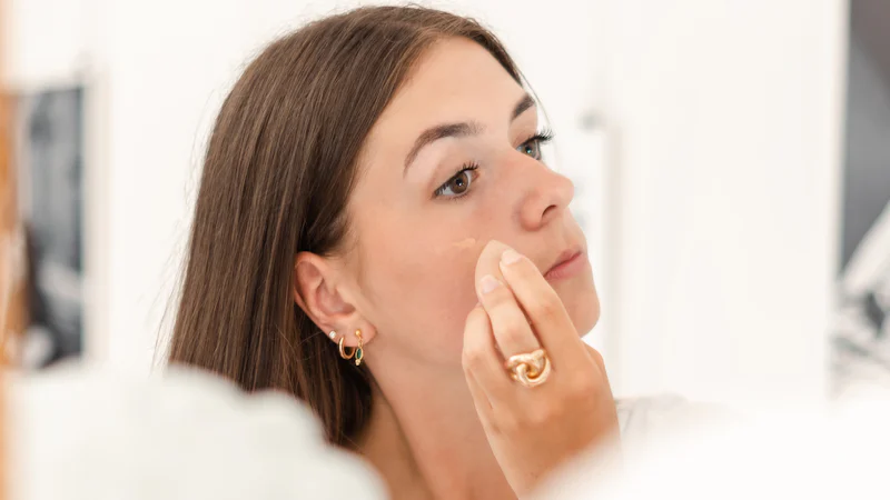 Phụ nữ đưa tay lên má khi chăm sóc da buổi tối, minh họa thao tác thoa dưỡng nhẹ nhàng