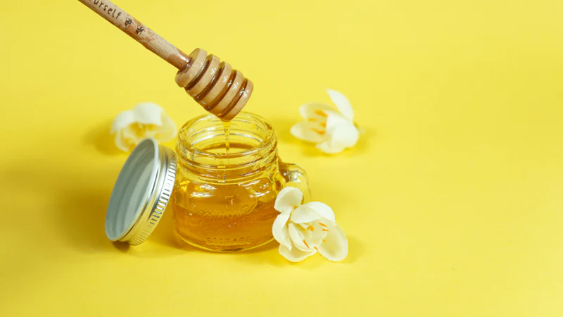 Hũ mật ong lên men chùm ngây màu vàng óng với que lấy mật
