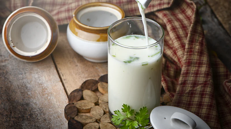 Ly sữa đặt cạnh rau lá xanh trên mặt bàn